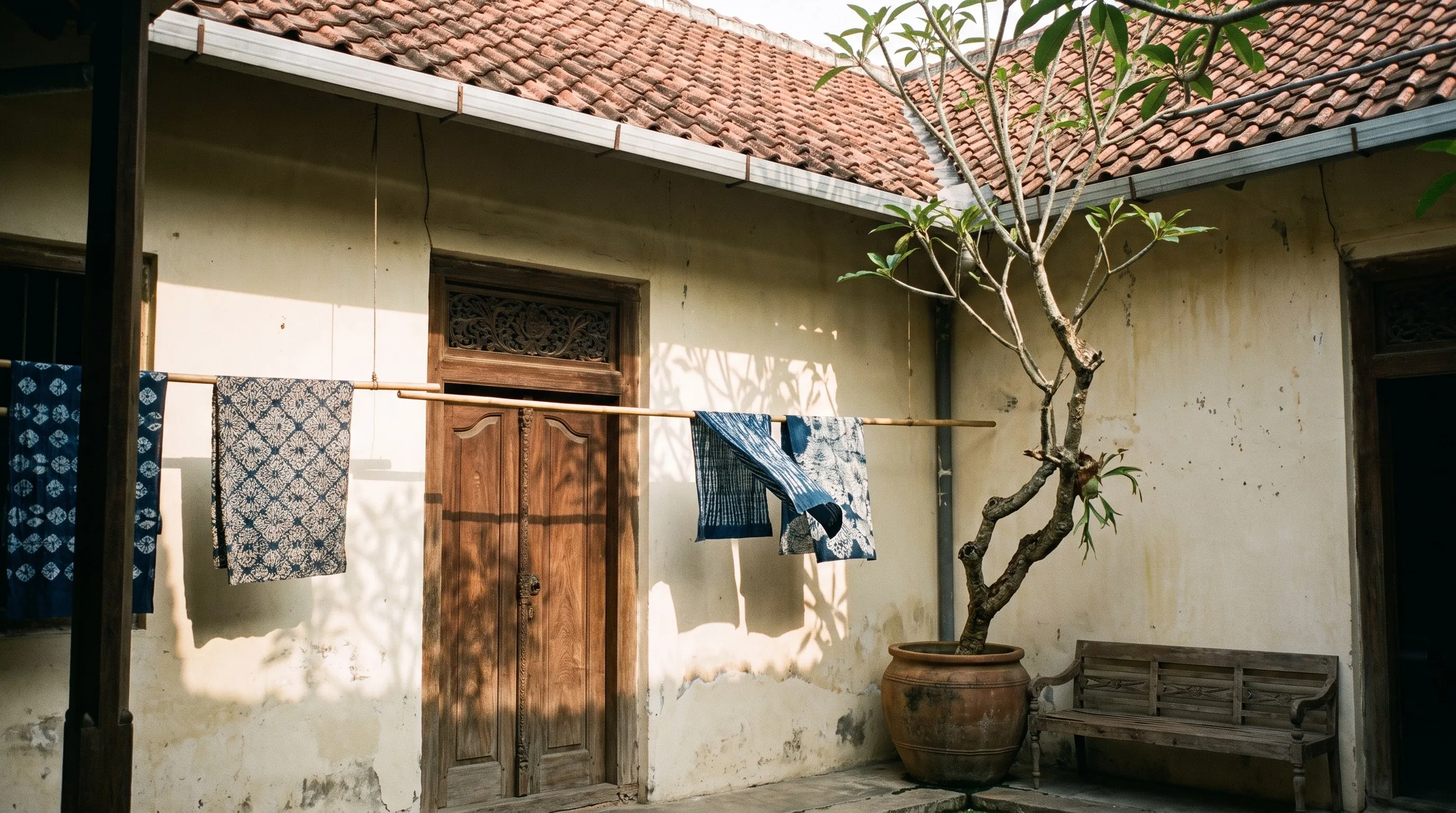 Halaman dalam rumah tua pecinan Lasem dengan dinding krem, atap genteng, dan kain-kain batik yang dijemur pada tali